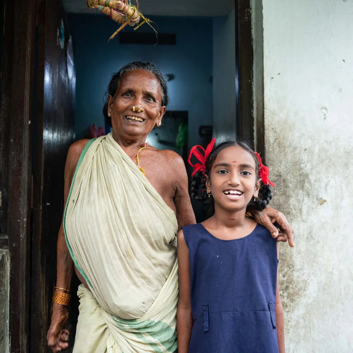 Woman and young girl standing together in a doorway, smiling.