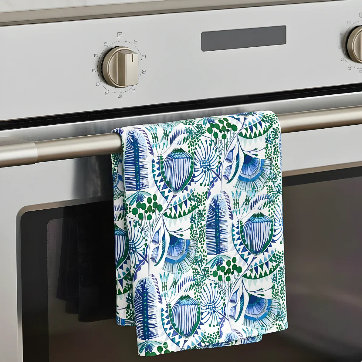 Towel with blue and green leaf pattern hanging on an oven handle