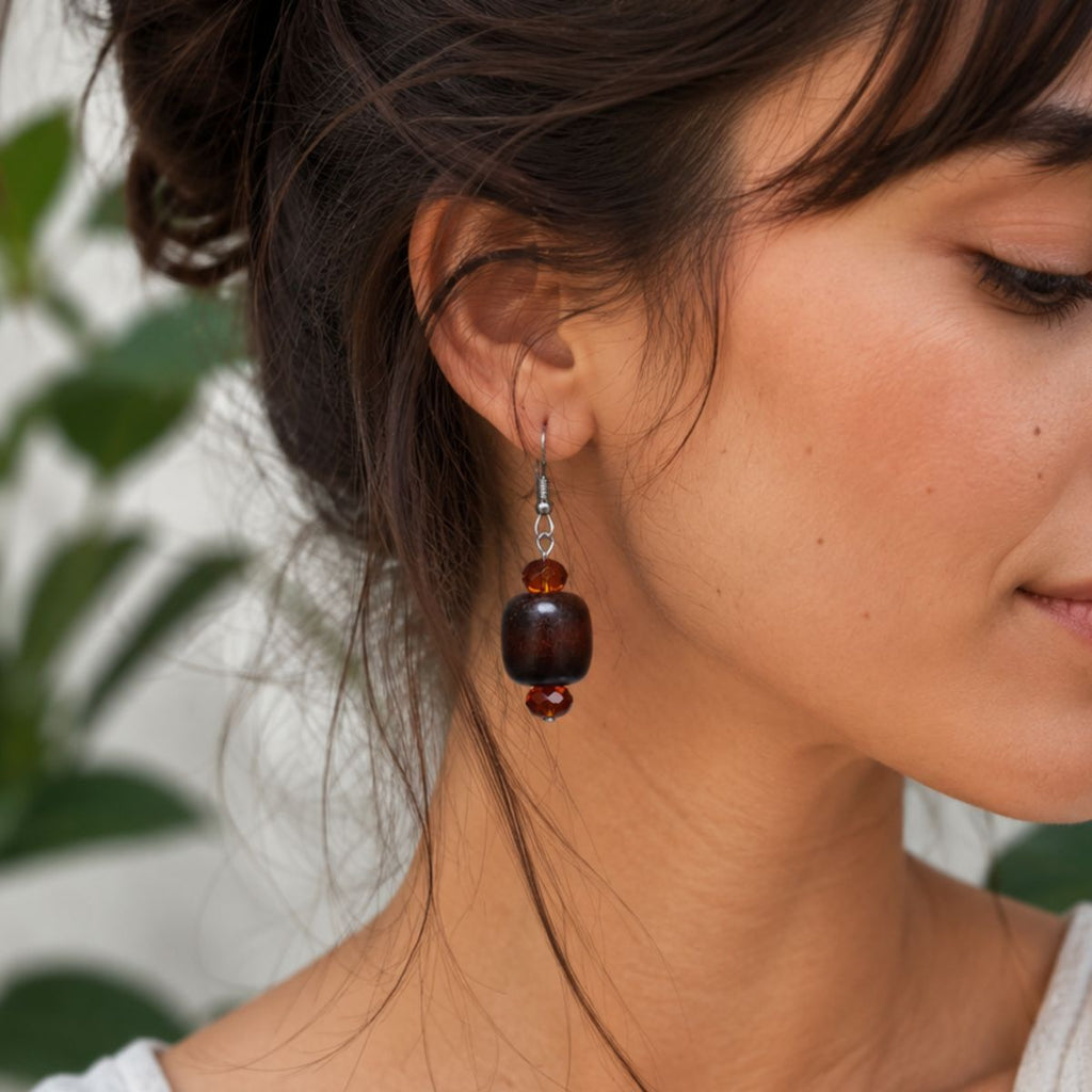 Close-up of a woman wearing a brown beaded earring with a blurred natural background