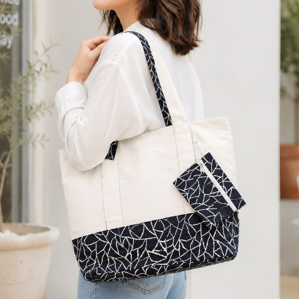 Person holding a white tote bag with black geometric pattern