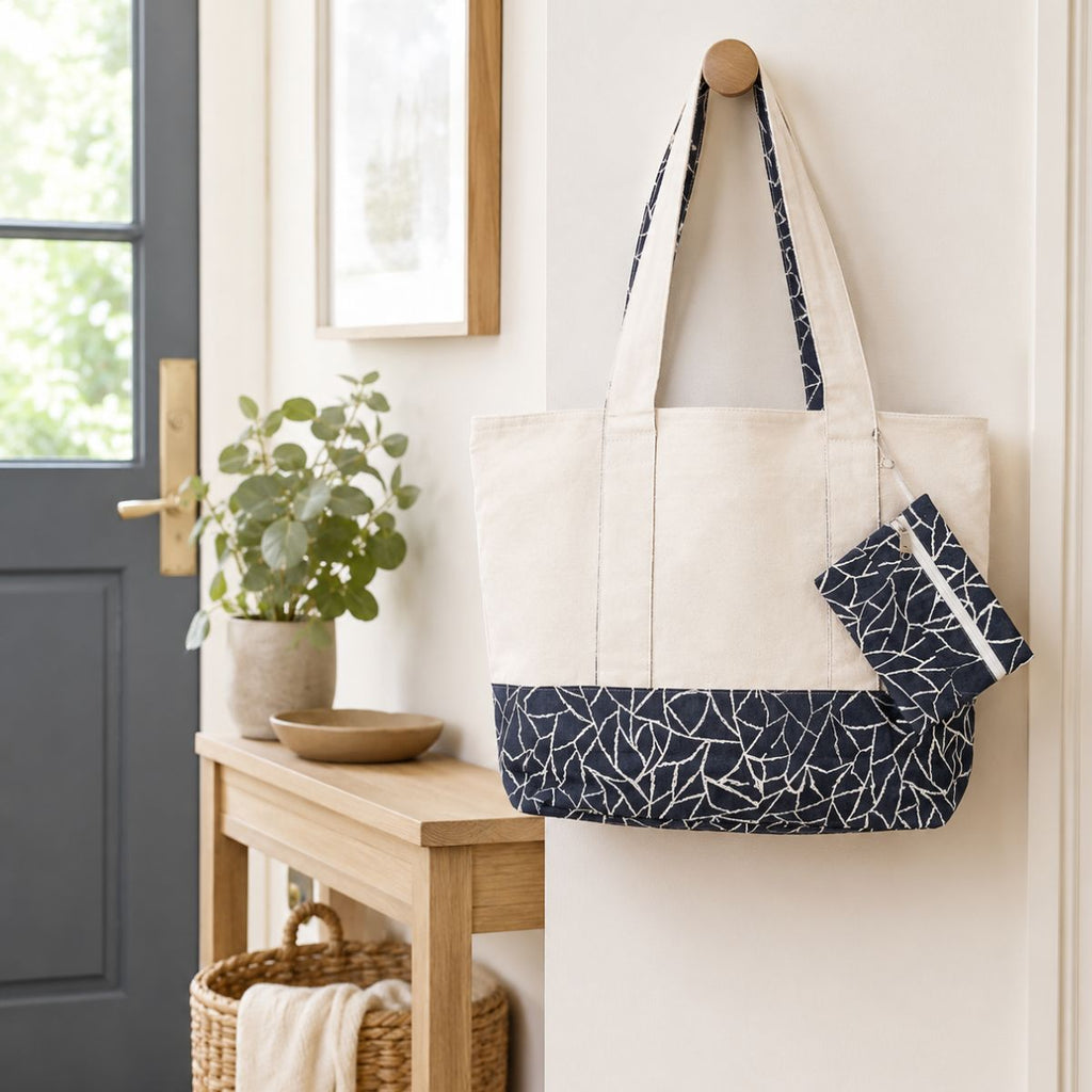 White tote bag with navy pattern hanging on a hook in a home entryway.