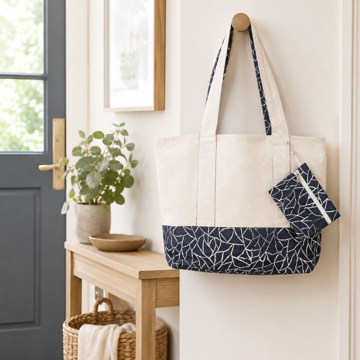 White tote bag with navy pattern hanging on a hook in a home entryway.