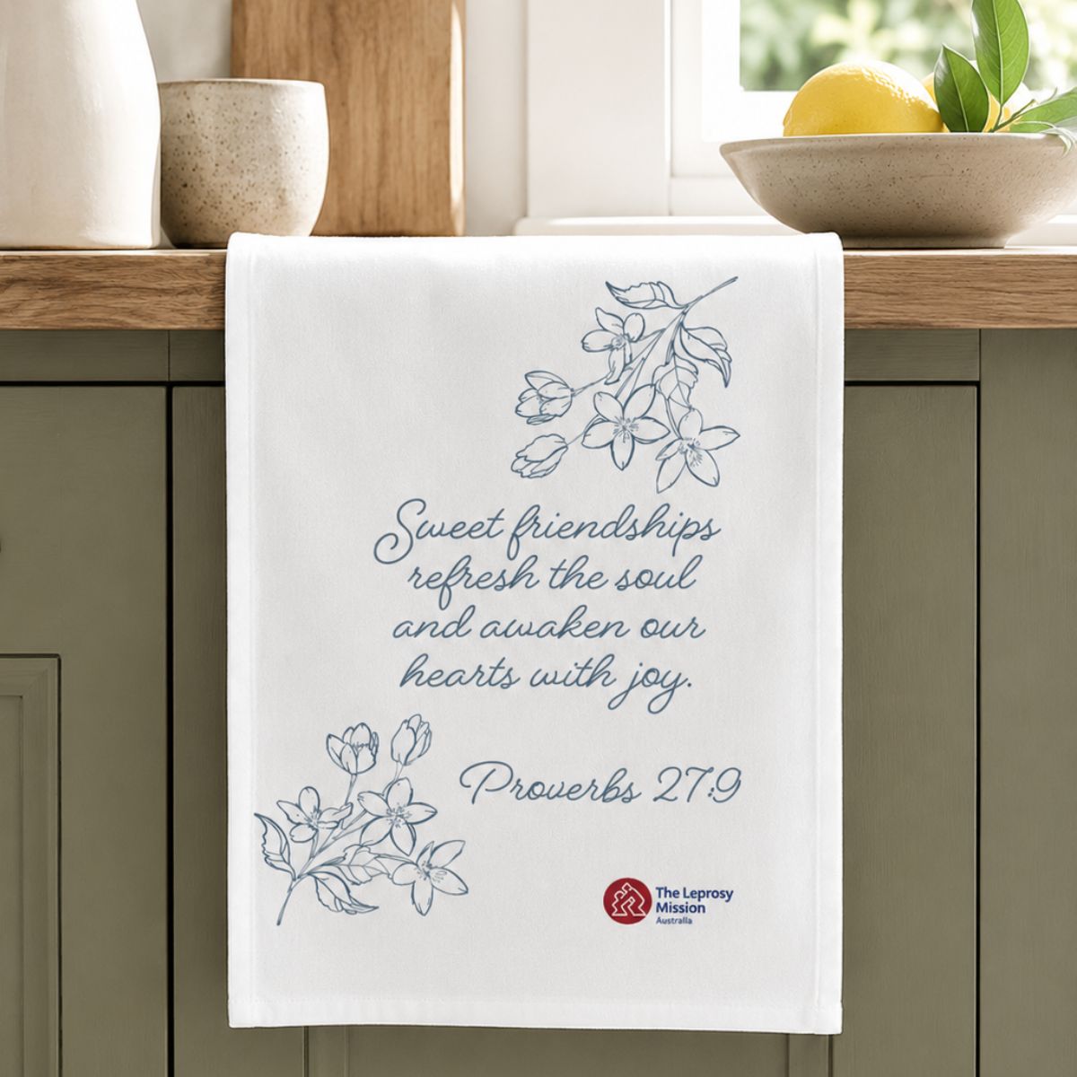 Kitchen towel with Proverbs 27:9 text and floral designs on a kitchen counter.