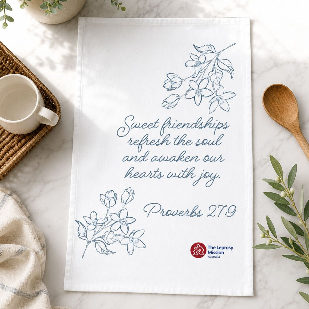 Tea towel with motivational quote and branding on a marble surface with a cup and spoon.