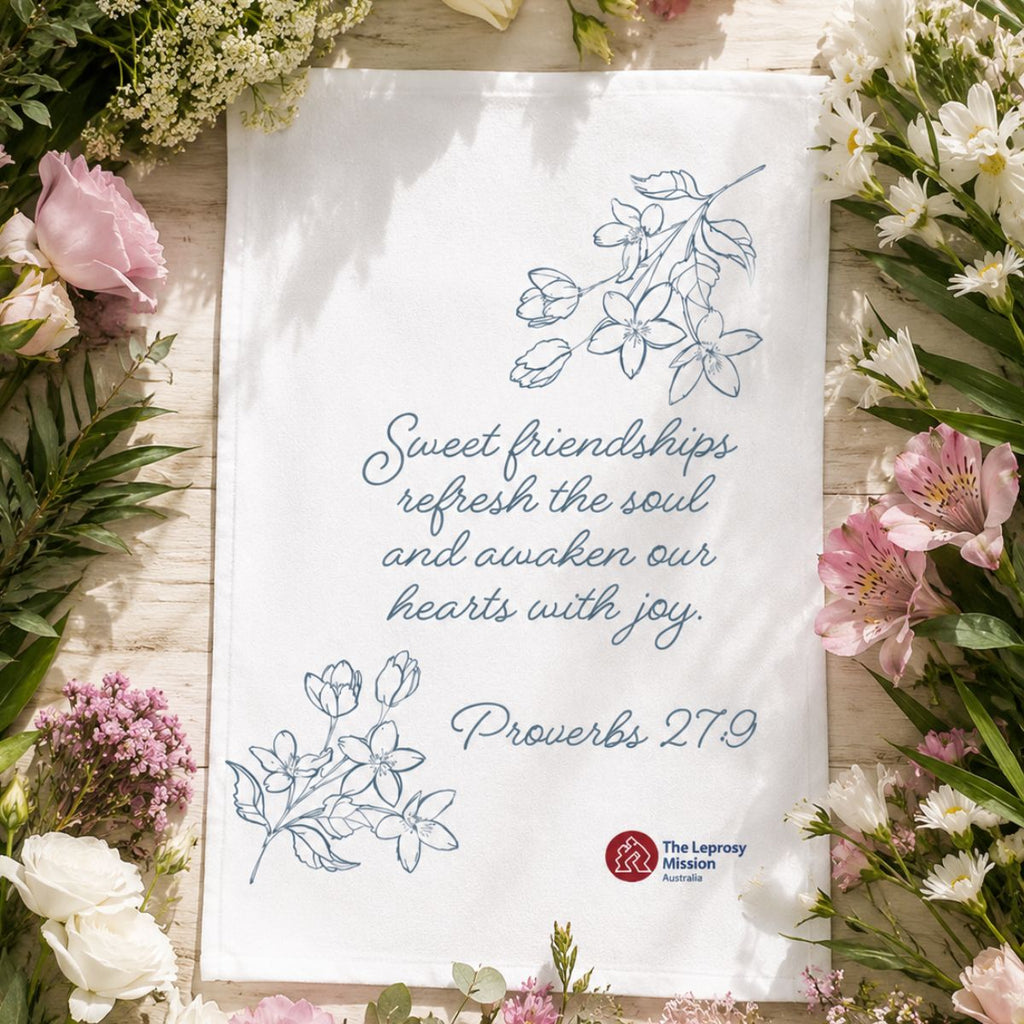 Sheet of paper with floral design and text surrounded by flowers on a wooden surface