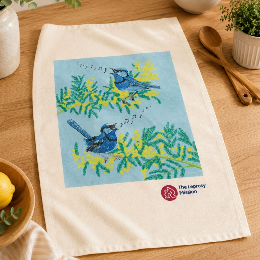 Towel with bird design and Leprosy Mission logo on a wooden surface