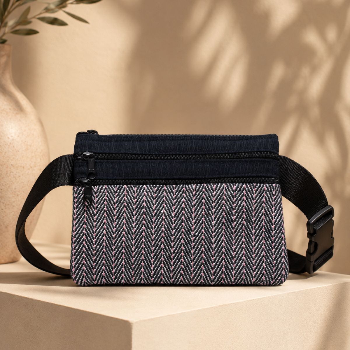 Black and white patterned waist bag on a beige surface with a neutral background