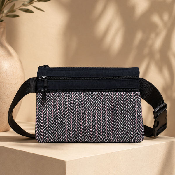 Black and white patterned waist bag on a beige surface with a neutral background