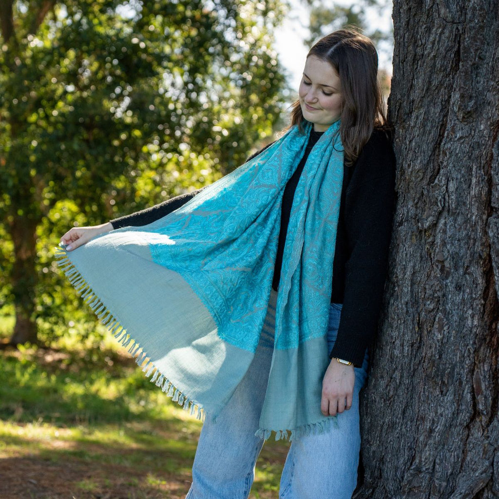 Women in blue scalf leaning against a tree