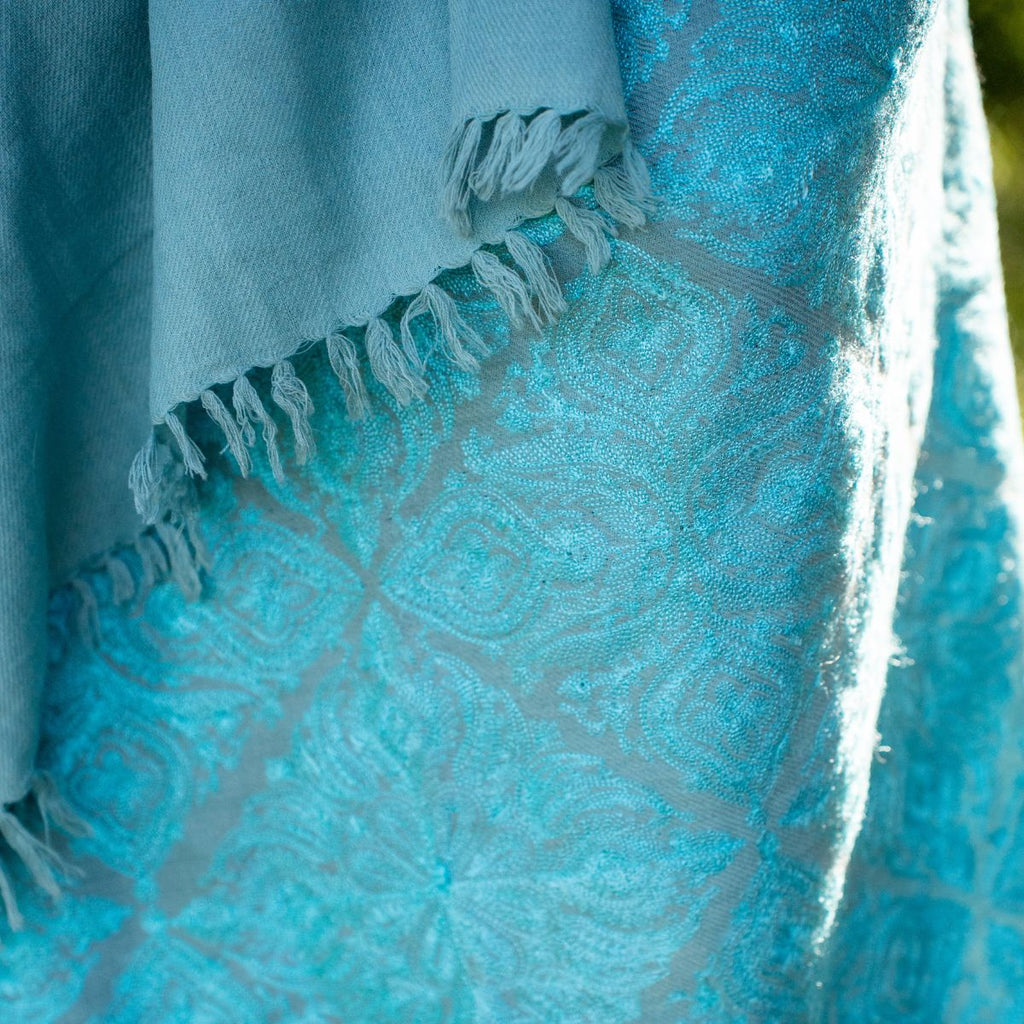 Close-up of a blue fabric with intricate patterns and frayed edges.
