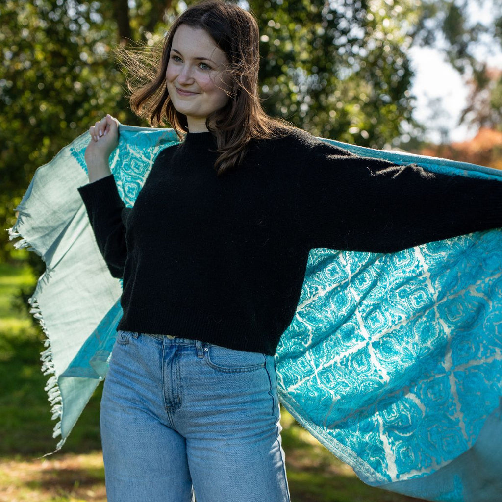 Woman holding a blue patterned fabric outdoors