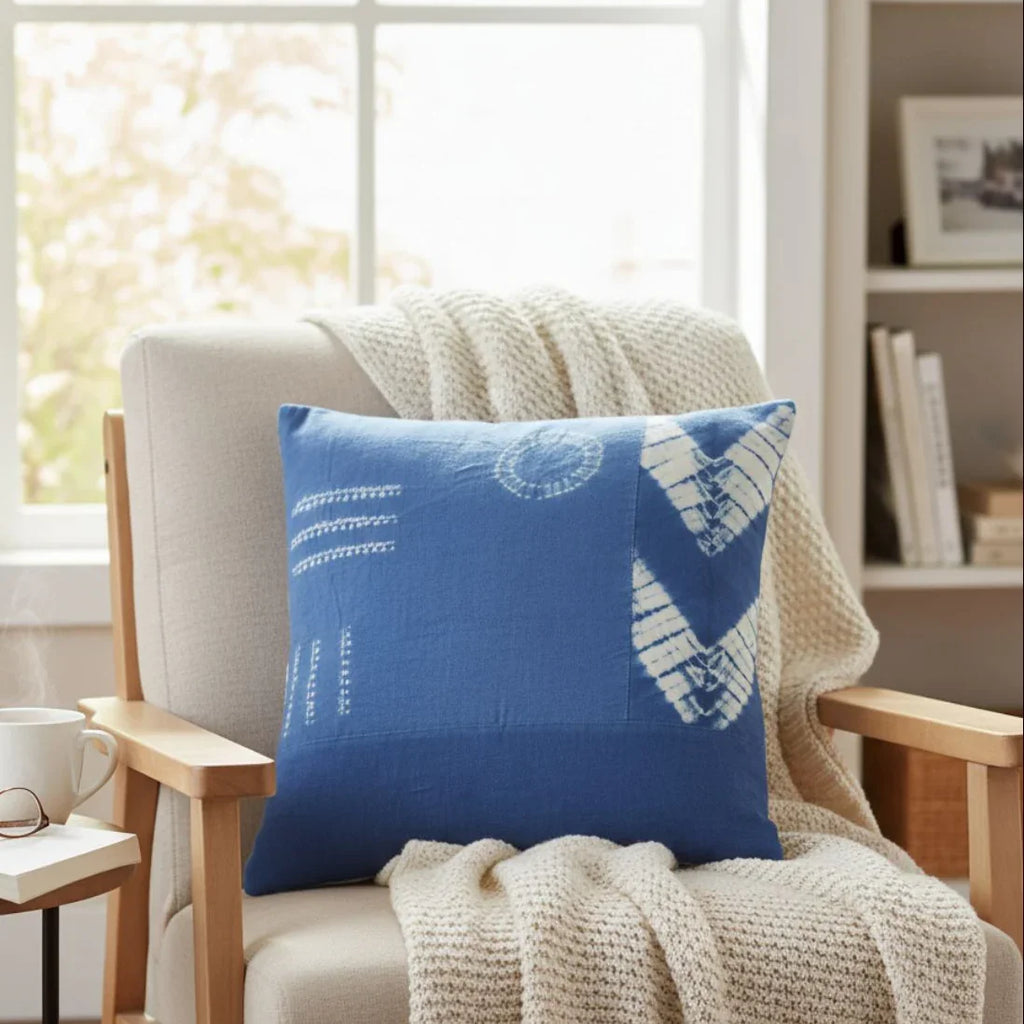 Blue pillow with white patterns on a beige armchair in a cozy living room.