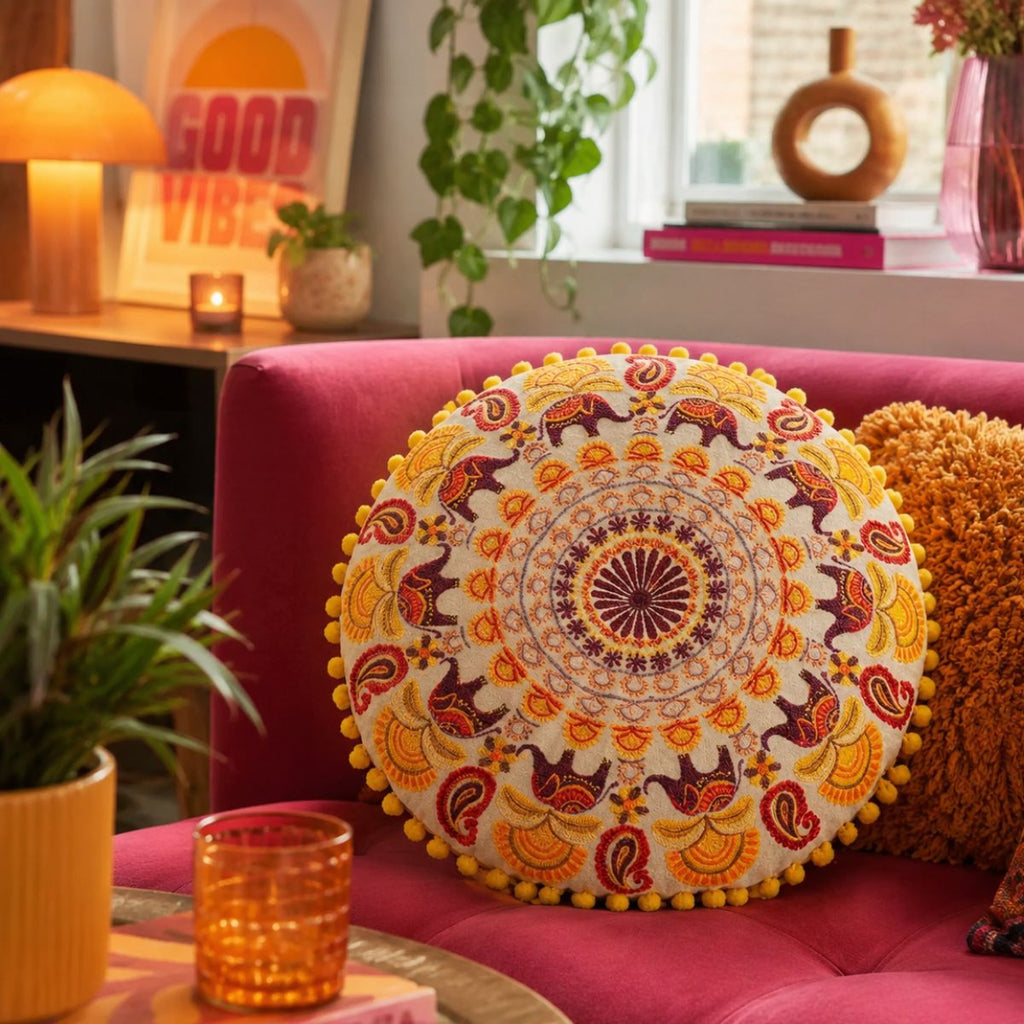 Decorative pillow with mandala design on a pink couch in a cozy living room.
