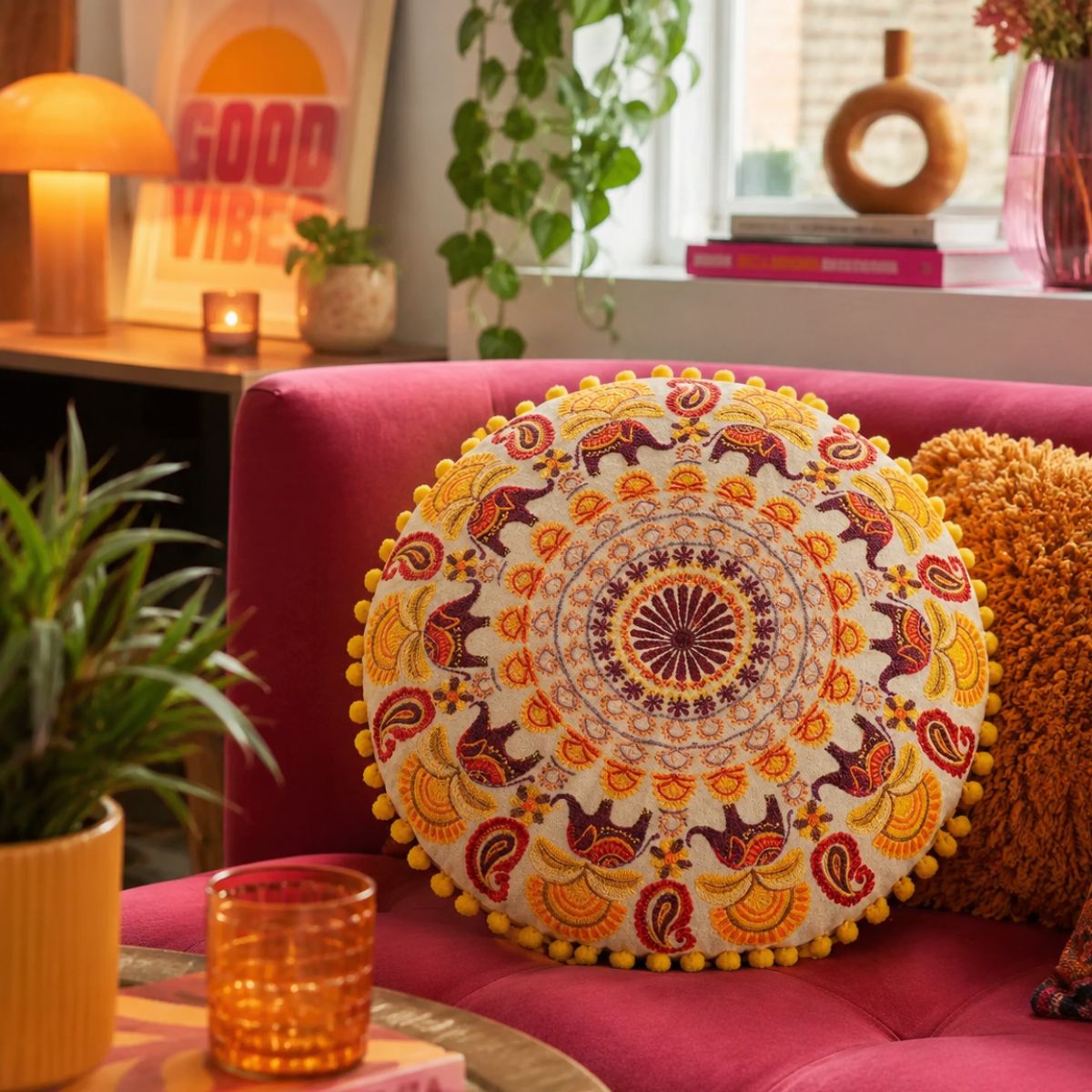 Decorative pillow with mandala design on a pink couch in a cozy living room.