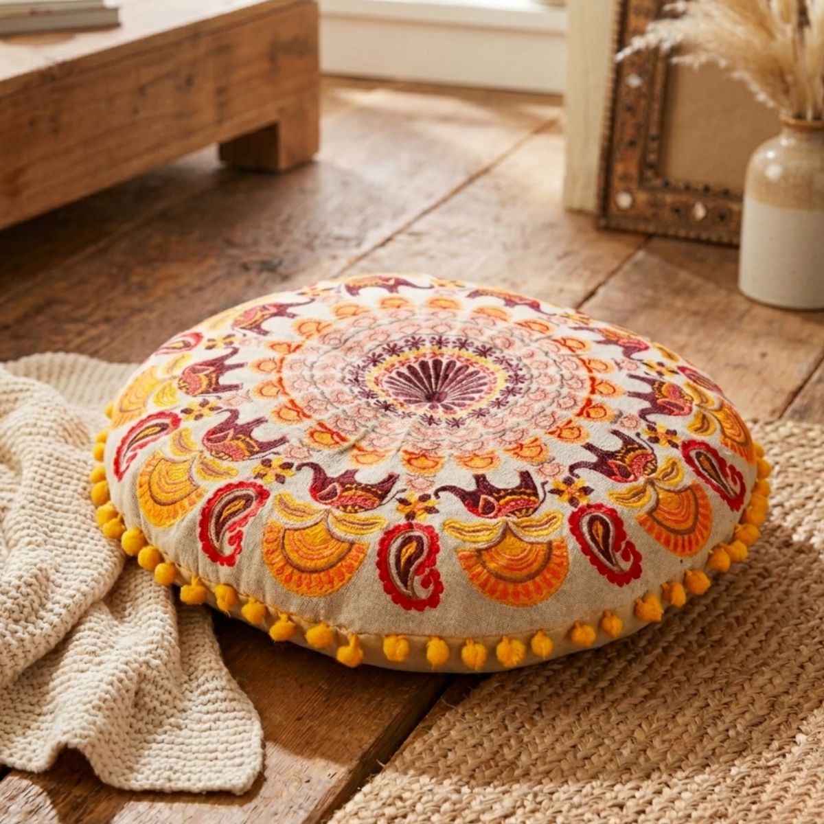 Decorative round pillow with colorful patterns on a wooden floor.