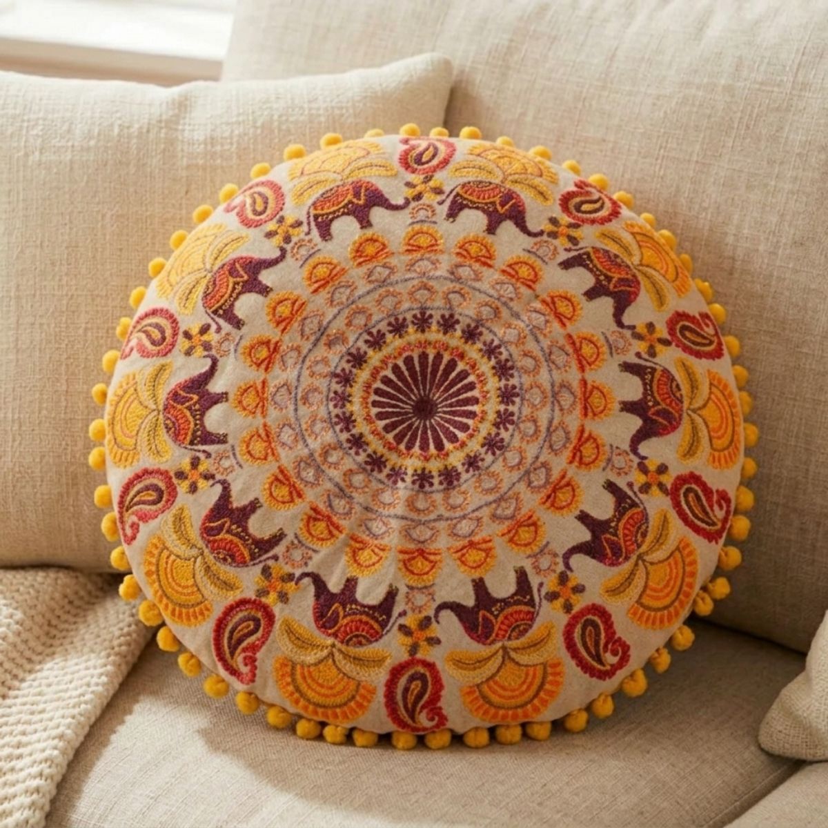 Decorative round pillow with elephant pattern on a beige sofa