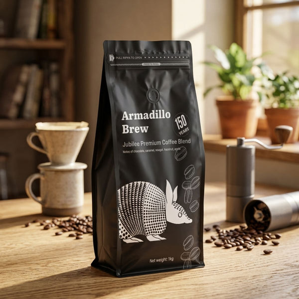 Black coffee bag labeled 'Armadillo Brew' on a wooden table with coffee-making equipment.