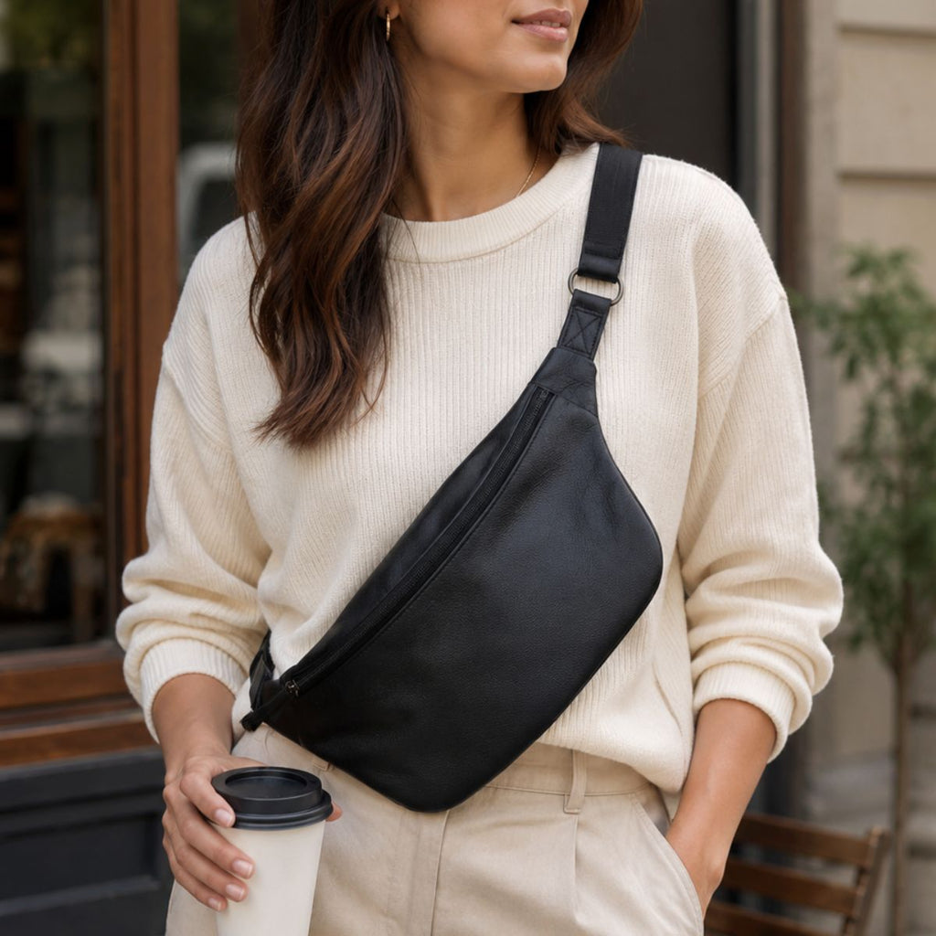 Woman wearing a black crossbody bag and holding a coffee cup outdoors.
