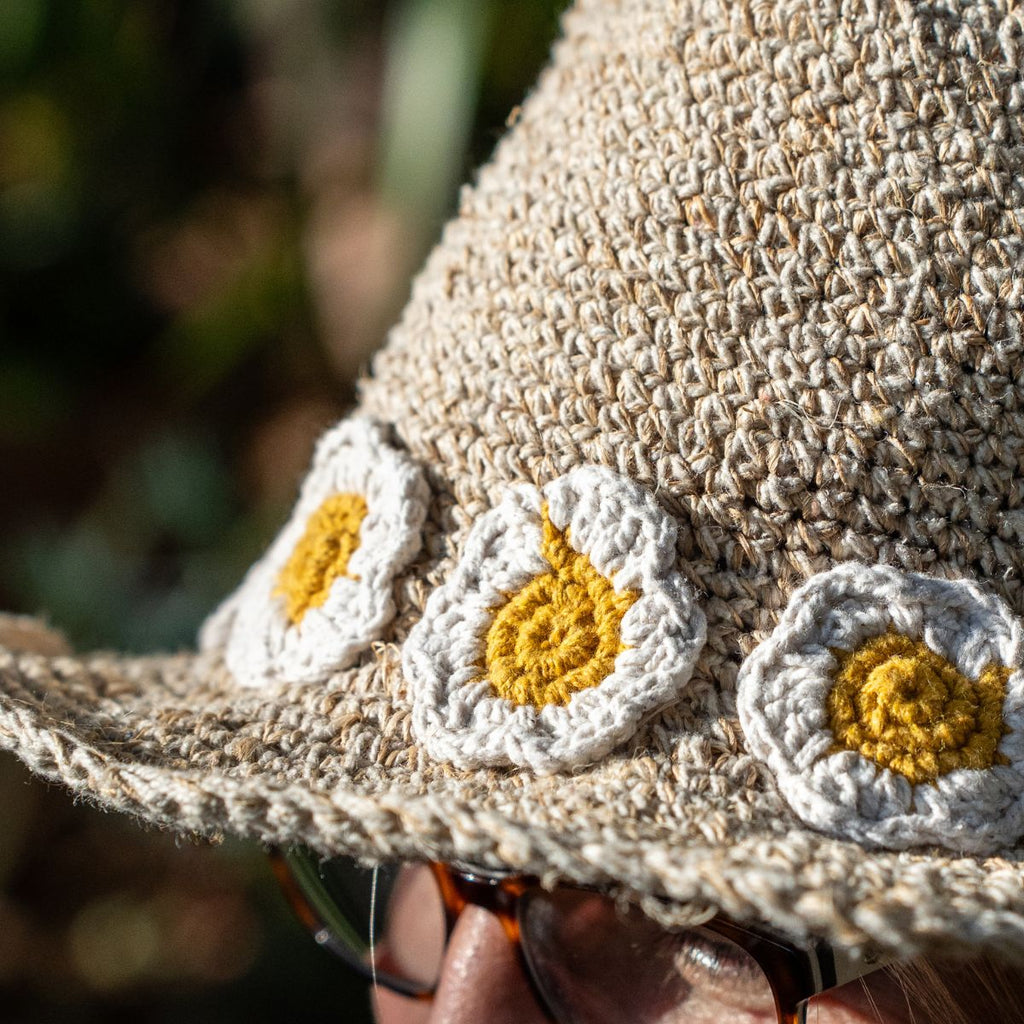 Close-up of a woven hat with floral patterns held by a person.