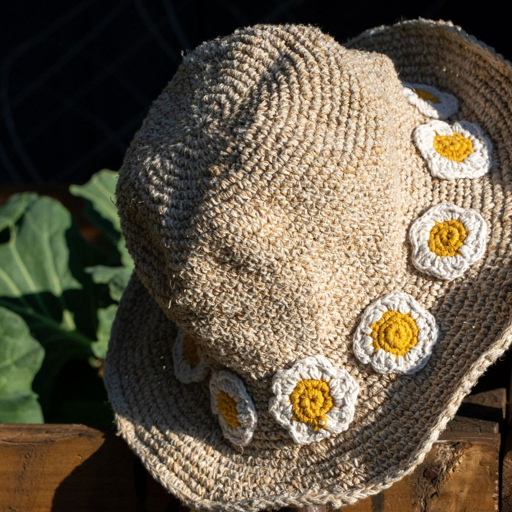 Crocheted sun hat with floral patterns on a wooden surface
