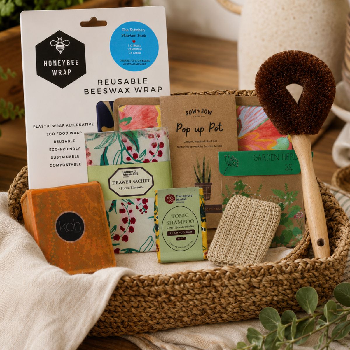 Collection of eco-friendly products including reusable beeswax wrap, plant pots, and cleaning brush in a woven basket.