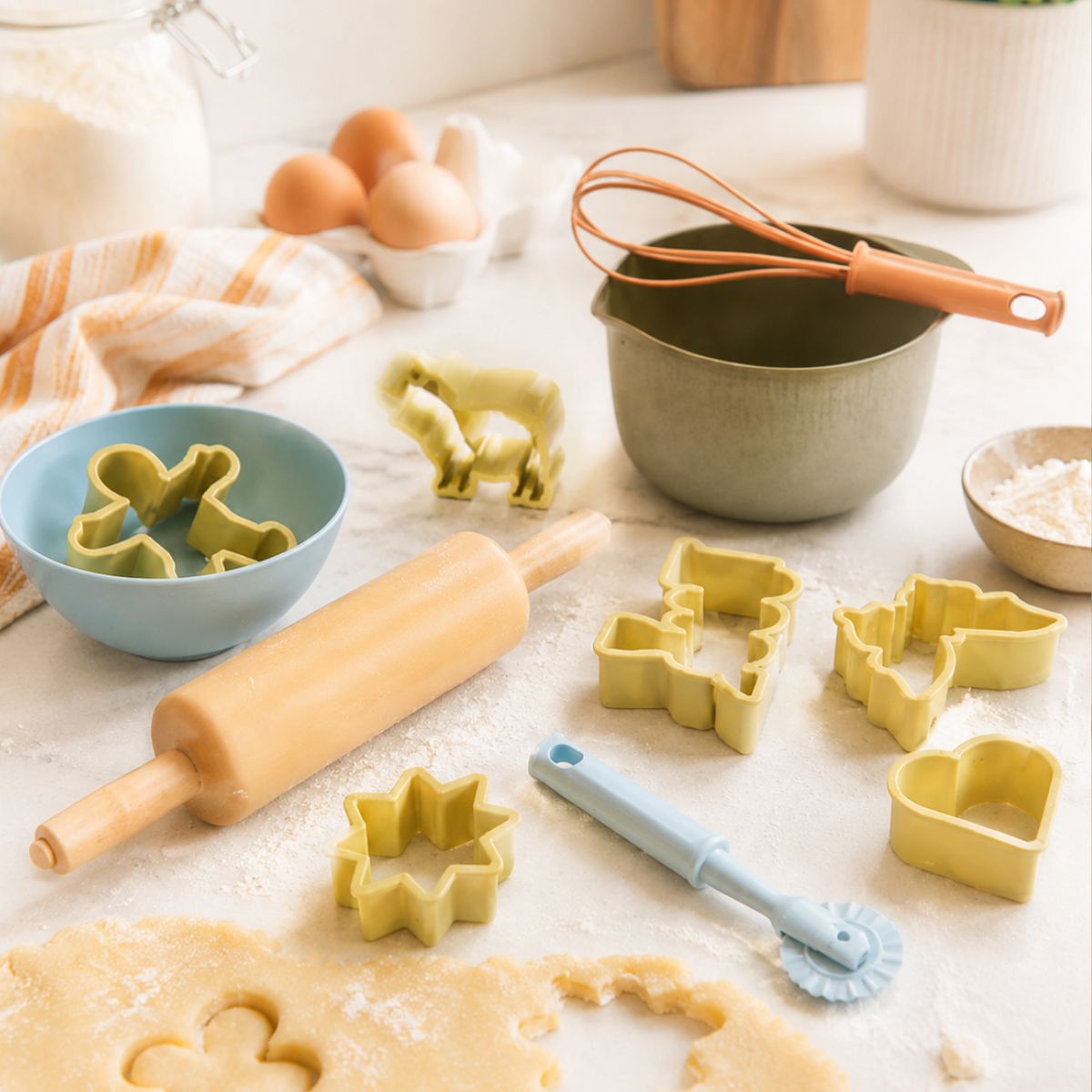 Baking tools and ingredients on a countertop including cookie cutters, rolling pin, and whisk.