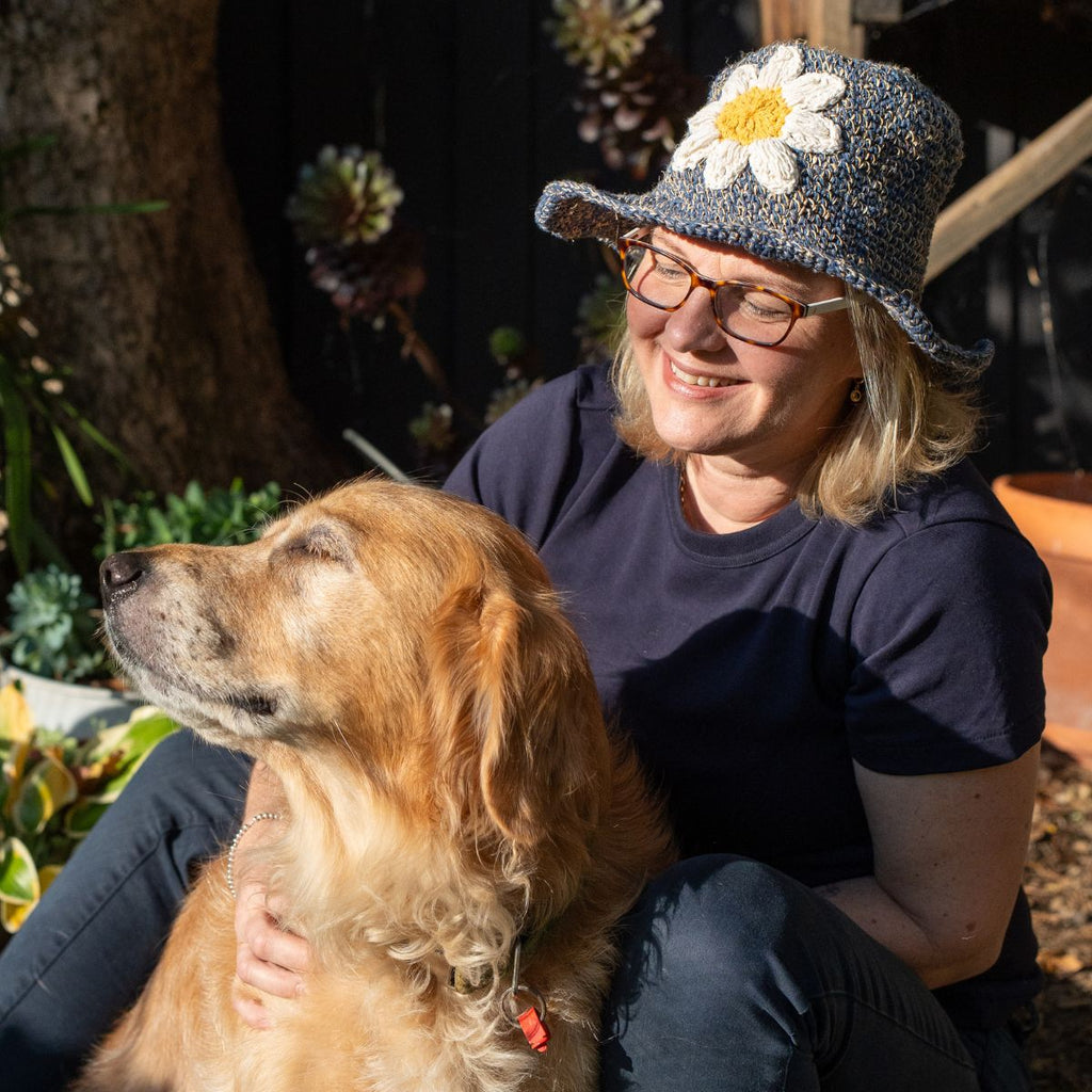 Women wearing a flower sun hat and dog sitting in the garden