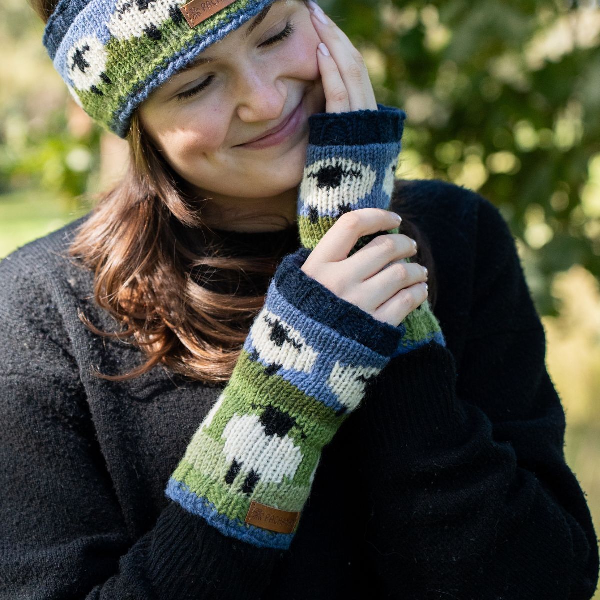 Person wearing a knitted hat and mittens with sheep pattern outdoors