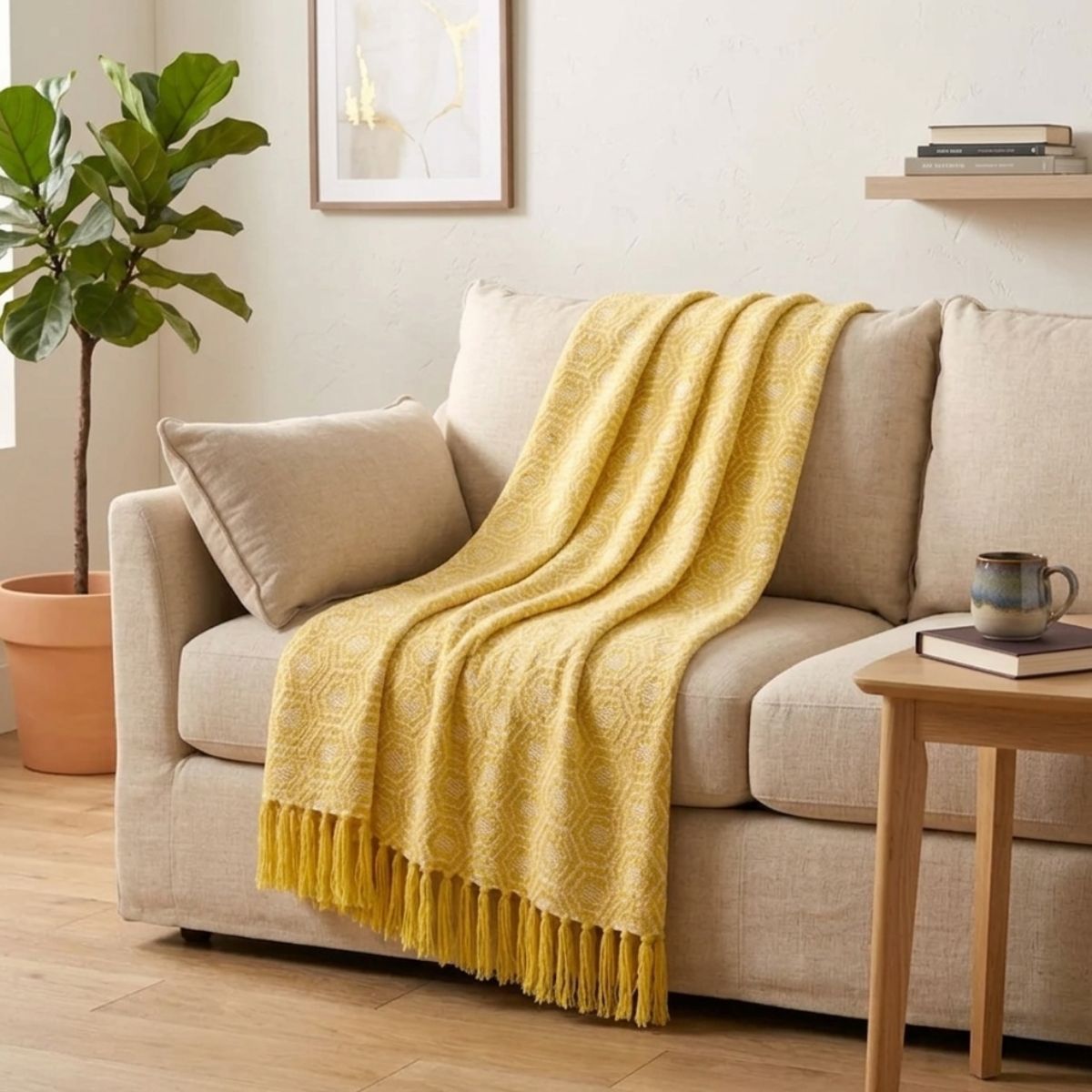 Yellow blanket draped over a beige sofa in a living room setting with a plant and side table.