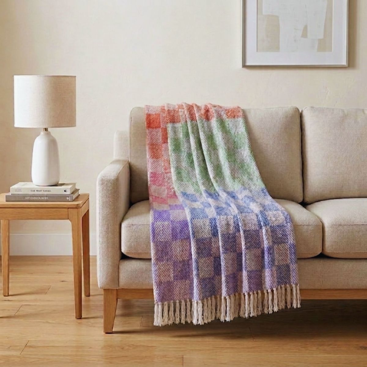 Colorful plaid blanket draped over a beige sofa in a living room setting.