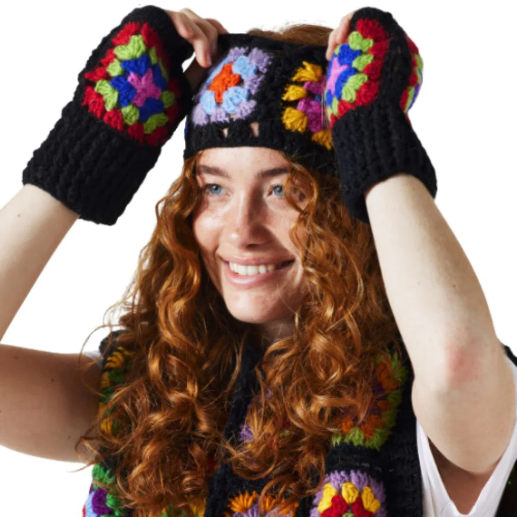 Person wearing a colorful knitted hat and gloves set on a white background