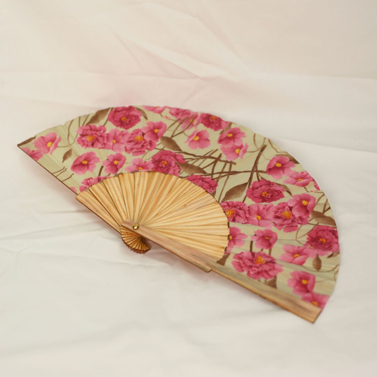 Handheld fan with pink floral design on a light background
