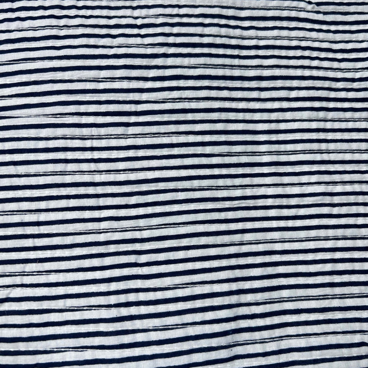 A close-up of a crinkled fabric with horizontal navy blue and white stripes.
