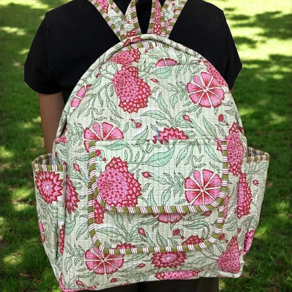 Floral-patterned backpack worn by a person on a grassy background