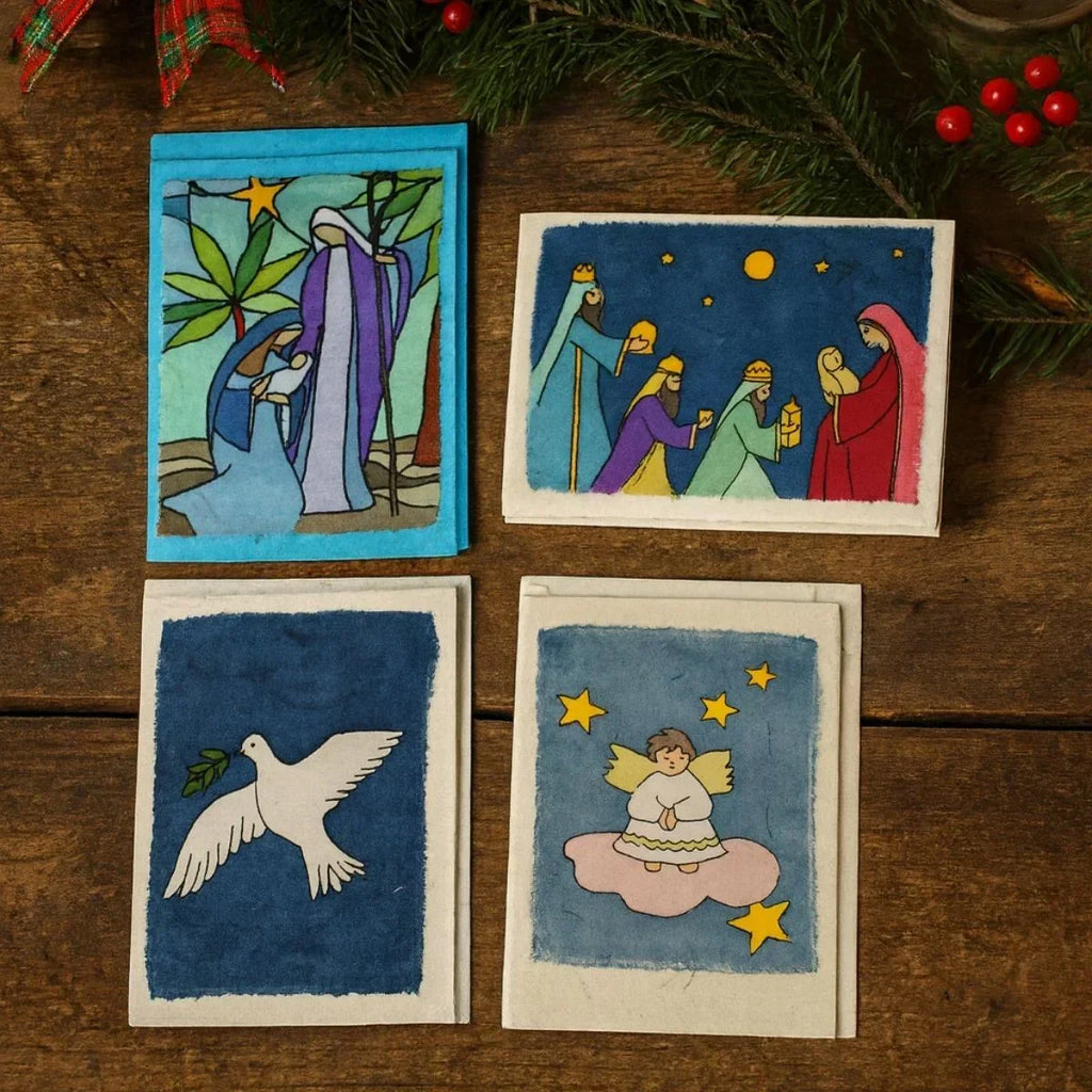 Four Christmas-themed cards on a wooden surface with festive decorations.