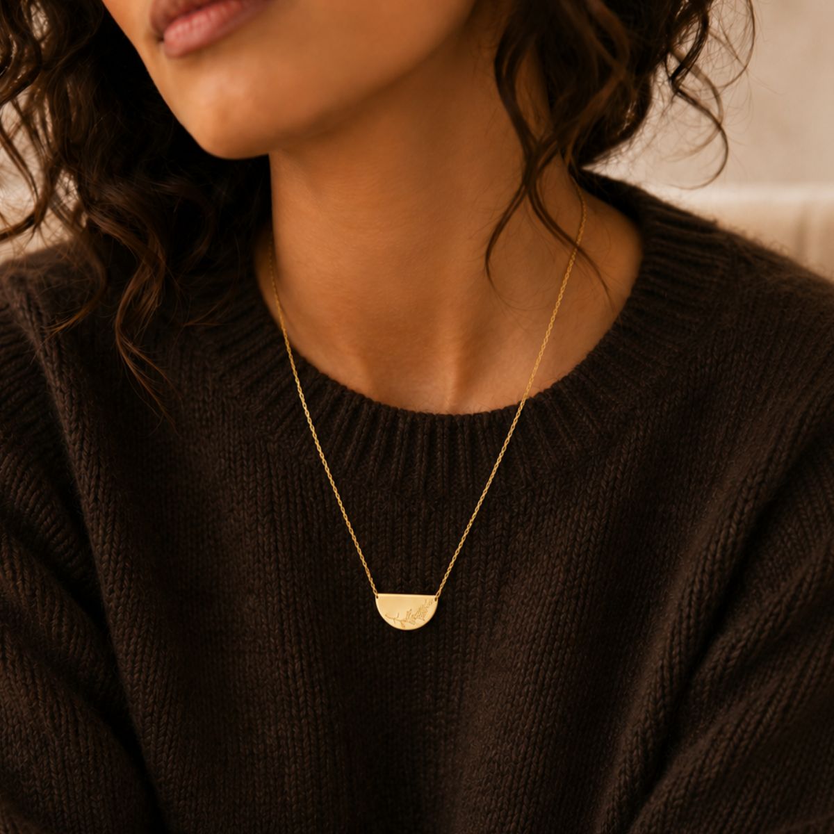 Close-up of a person wearing a gold necklace with a pendant.