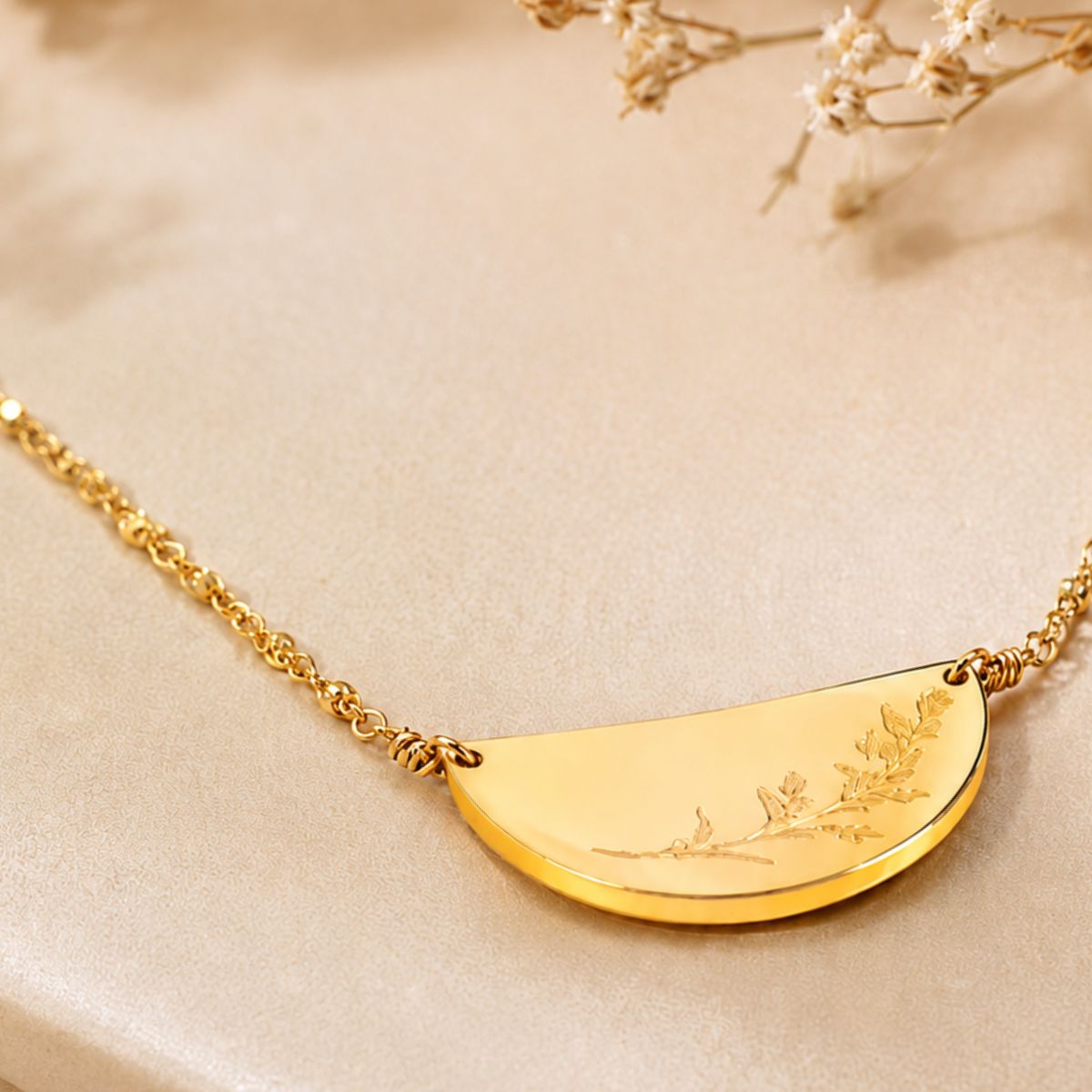 Gold necklace with a half-circle pendant on a beige background