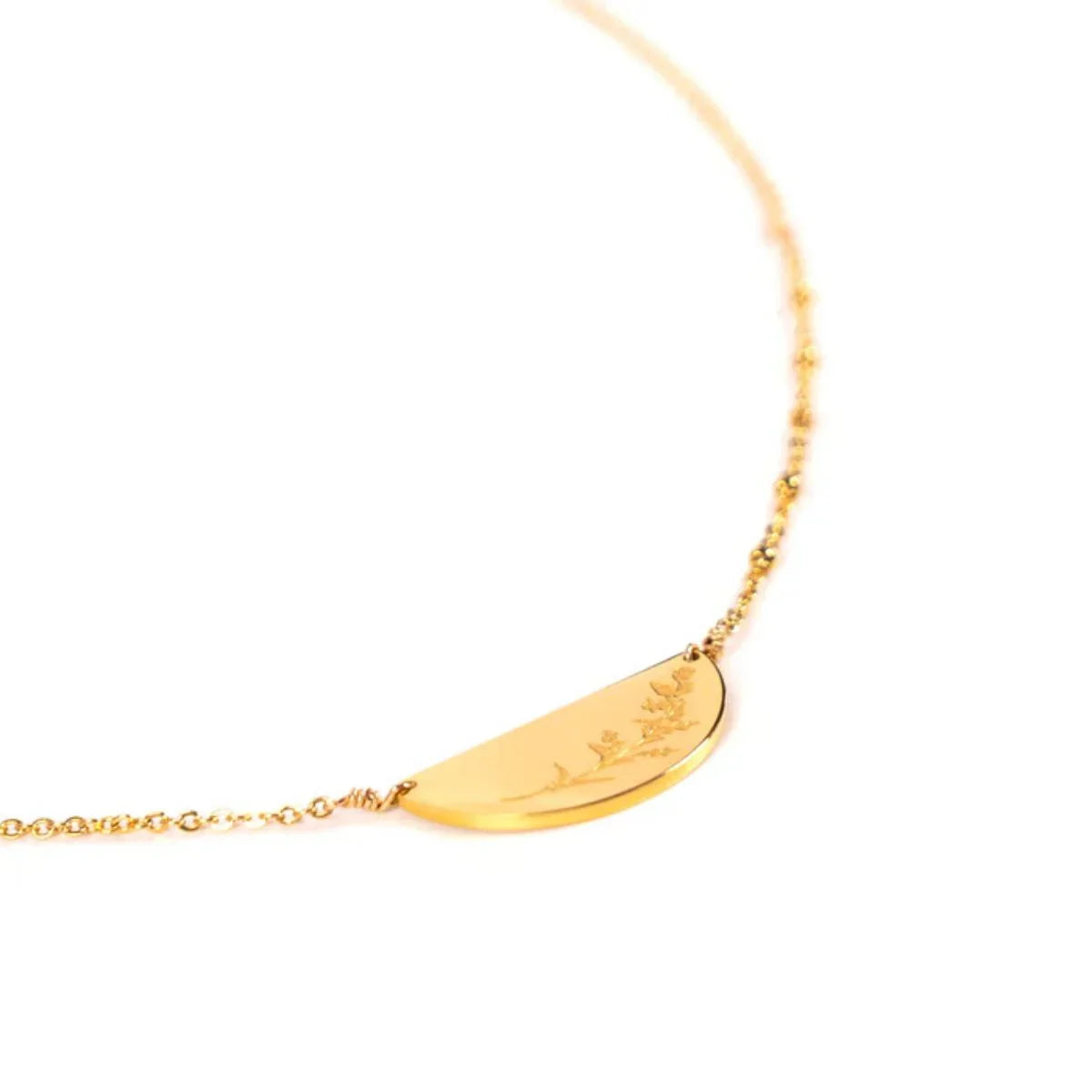 Gold necklace with a leaf-shaped pendant on a white background