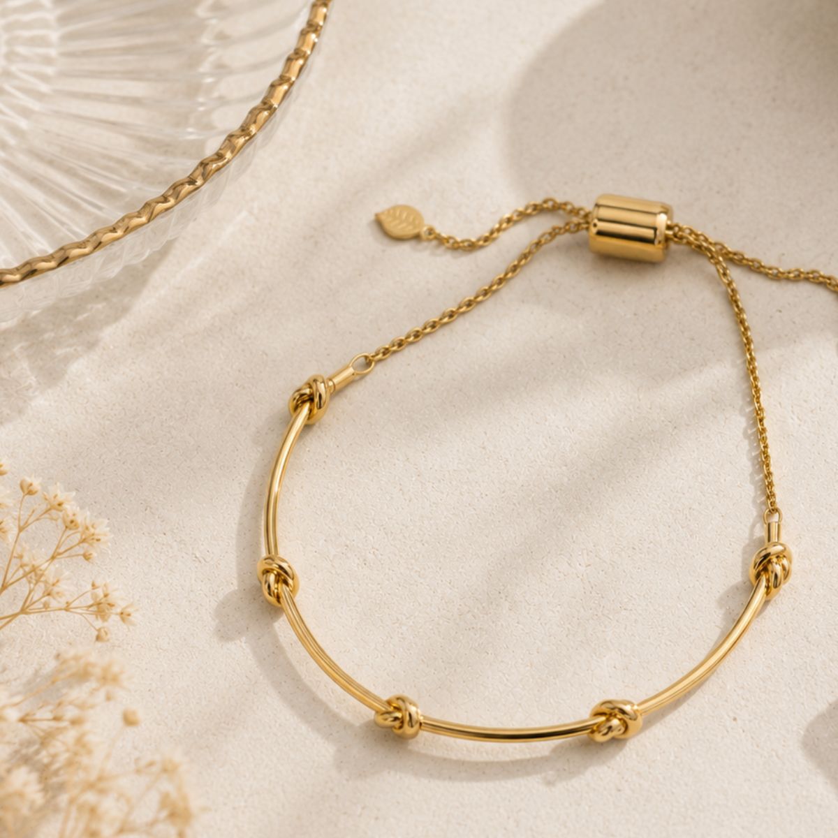 Gold bracelet on a light beige background with dried flowers