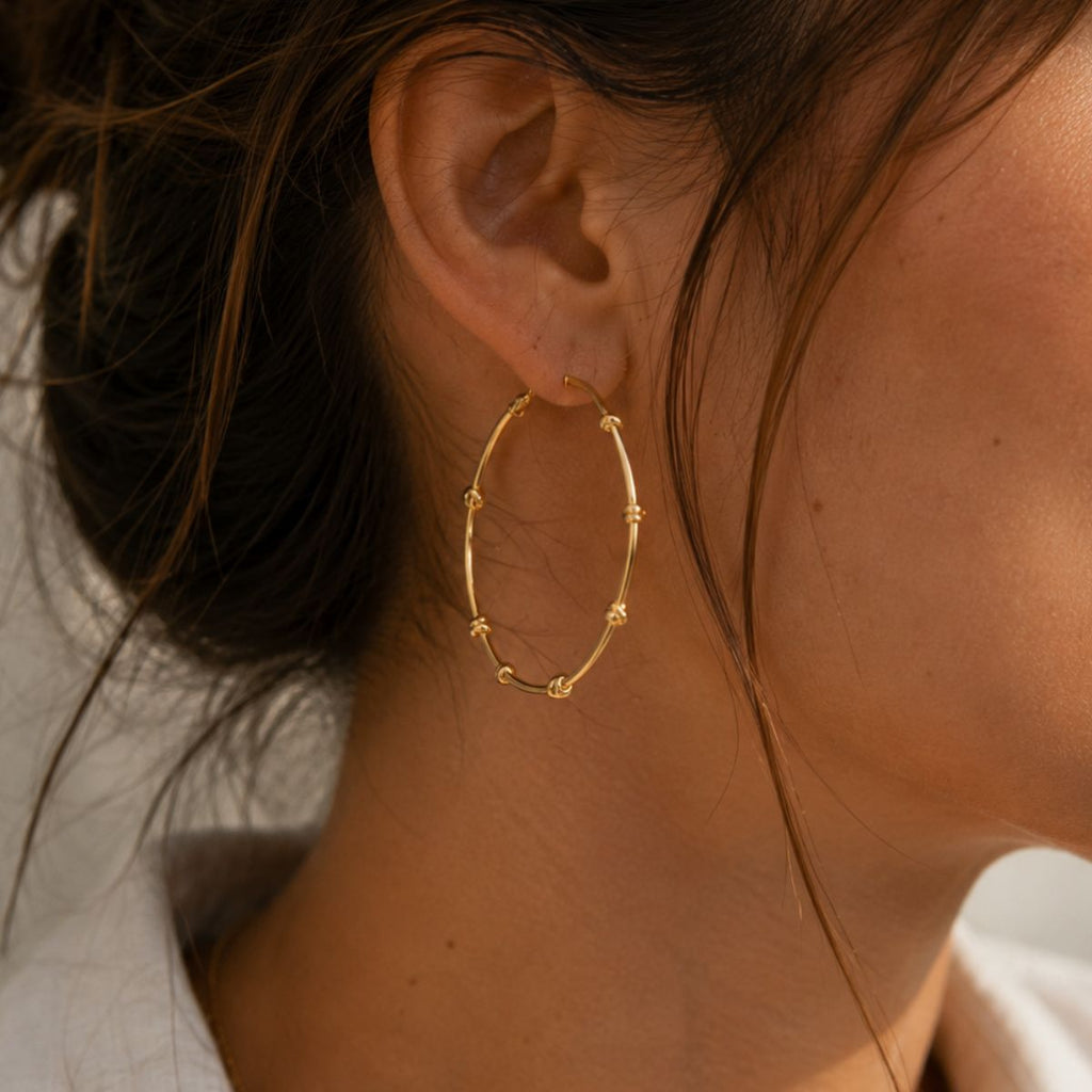 Close-up of a person wearing a gold hoop earring with soft lighting.