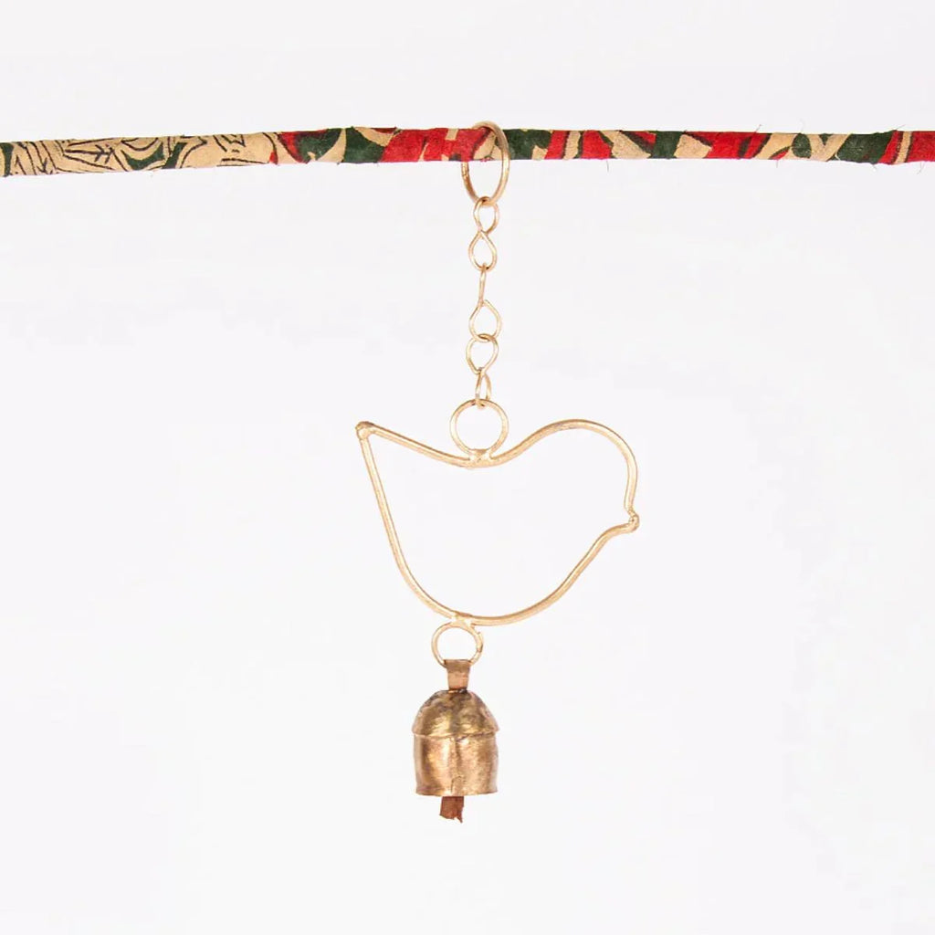 Decorative hanging with gold bird-shaped ornament and small bell on a white background