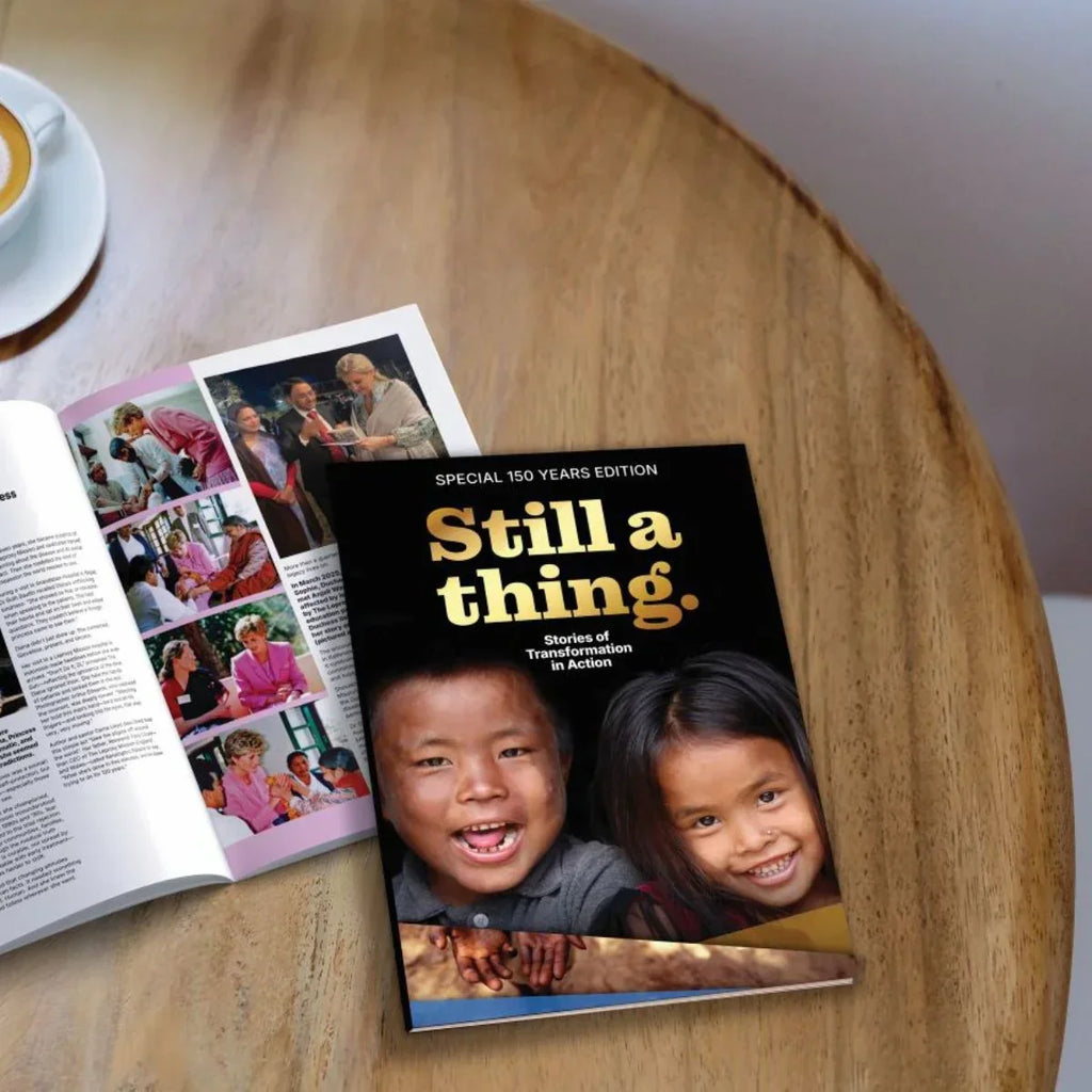 Book titled 'Still a thing.' with two children on the cover, placed on a wooden surface next to an open magazine.