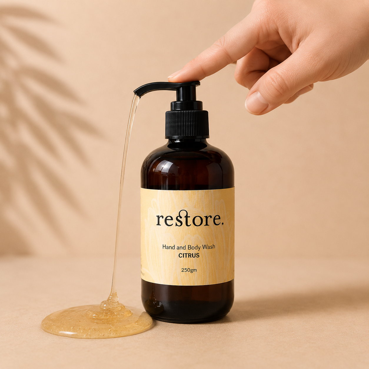 Hand holding a pump bottle of 'restore' hand and body wash with visible liquid flow on a beige background.
