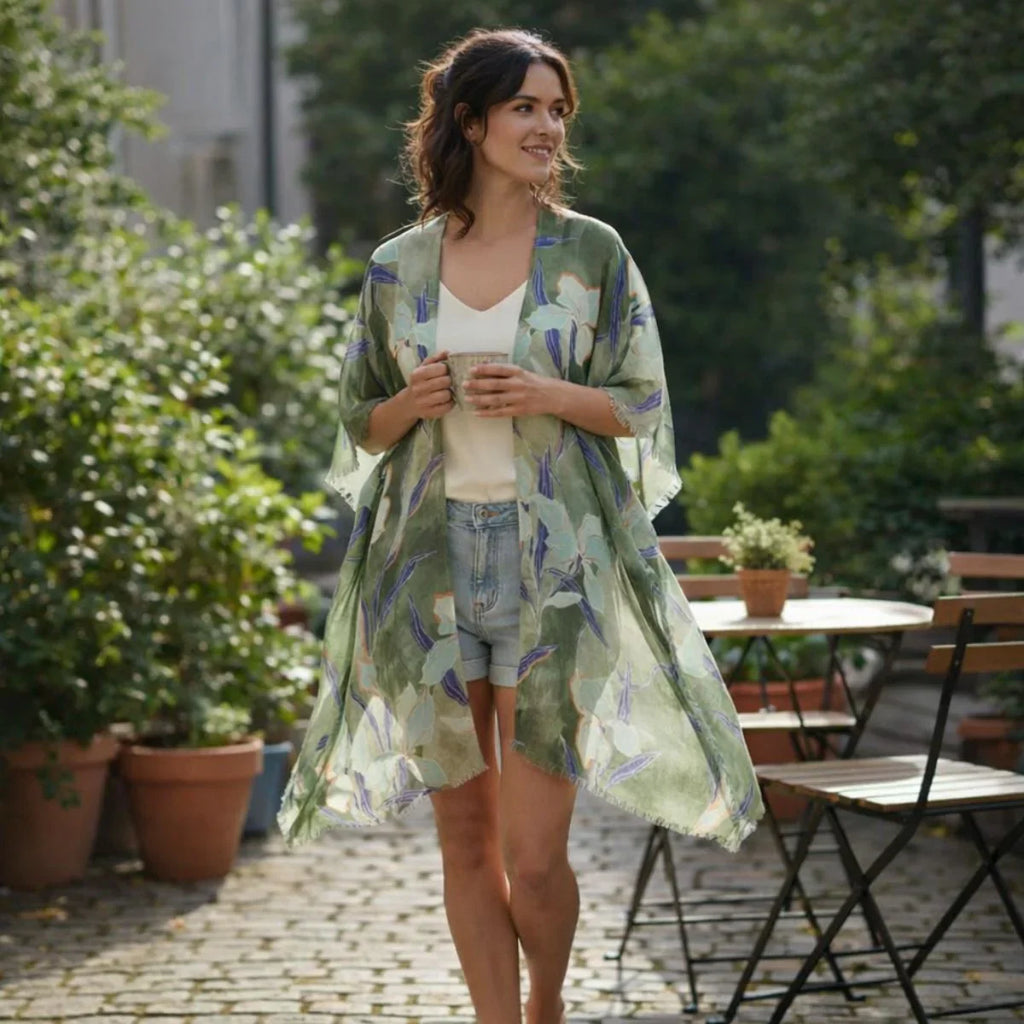 Woman wearing a green patterned kimono in an outdoor setting with plants and tables.
