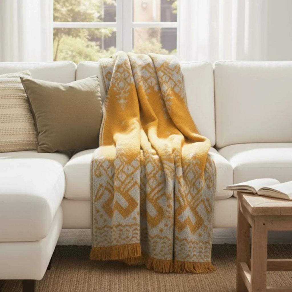 Yellow patterned blanket draped over a white sofa in a living room.