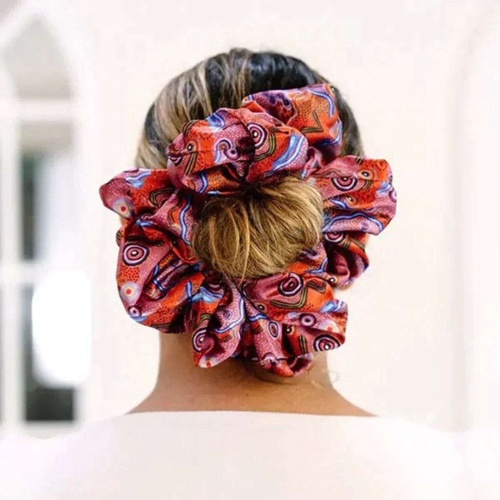 Person wearing a colorful patterned scrunchie on their hair against a blurred background
