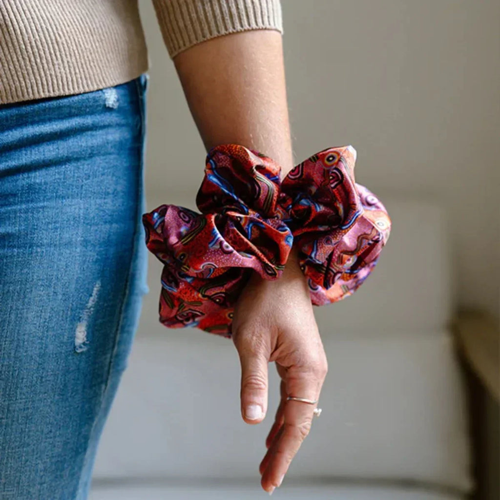 Hand holding a patterned scrunchie with a blurred background