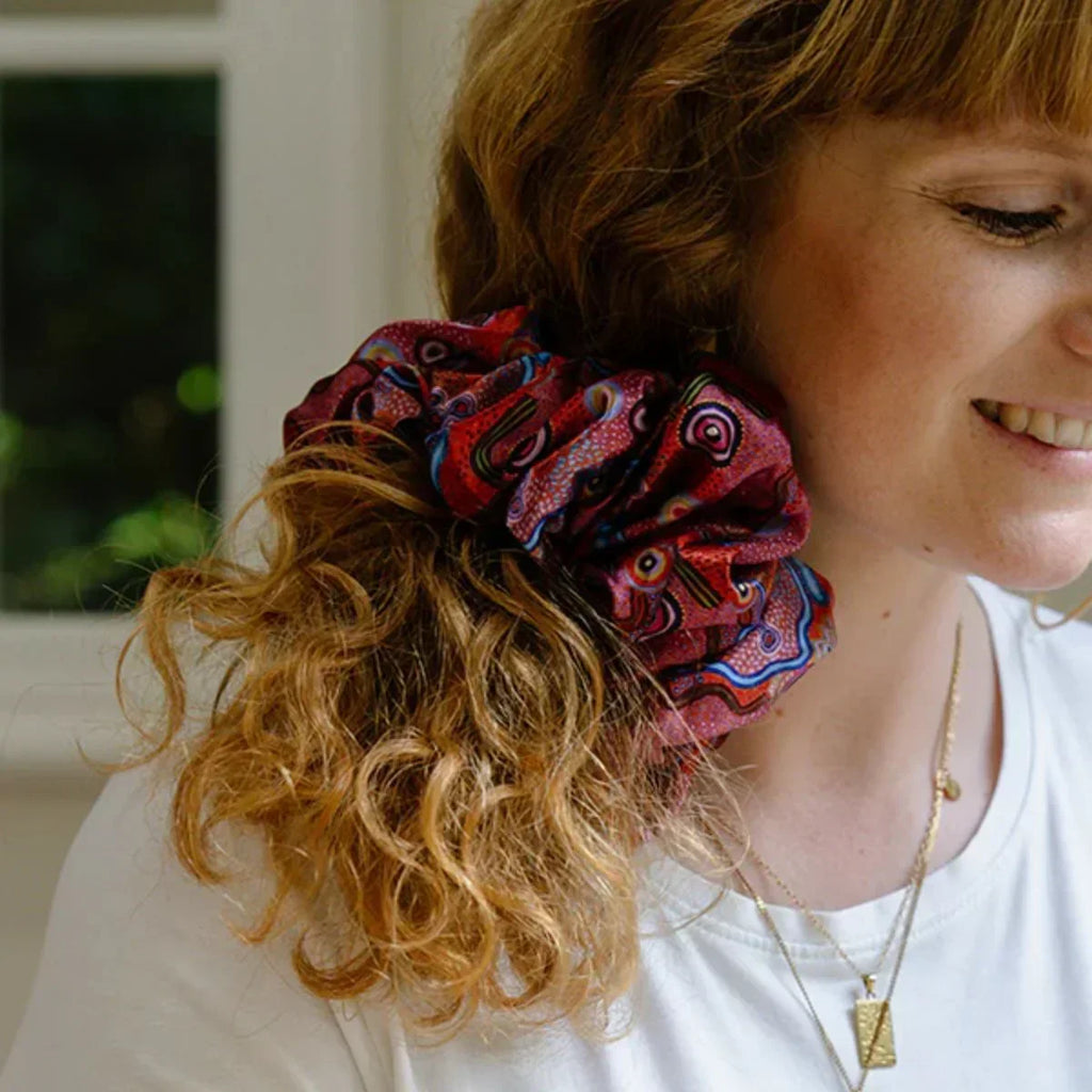 Person with a colorful scrunchie in their hair, wearing a white shirt.