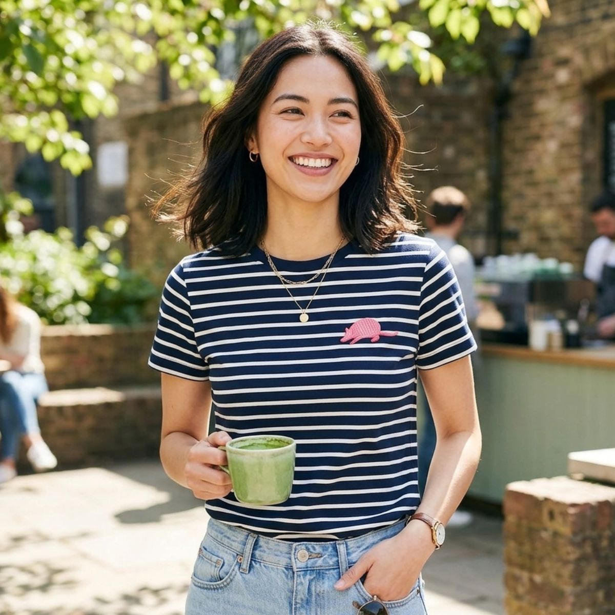 Woman in a striped shirt holding a green mug outdoors