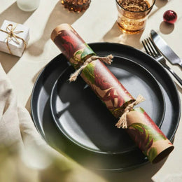 Decorative festive cracker for christmas paper roll on a black plate with a festive setting